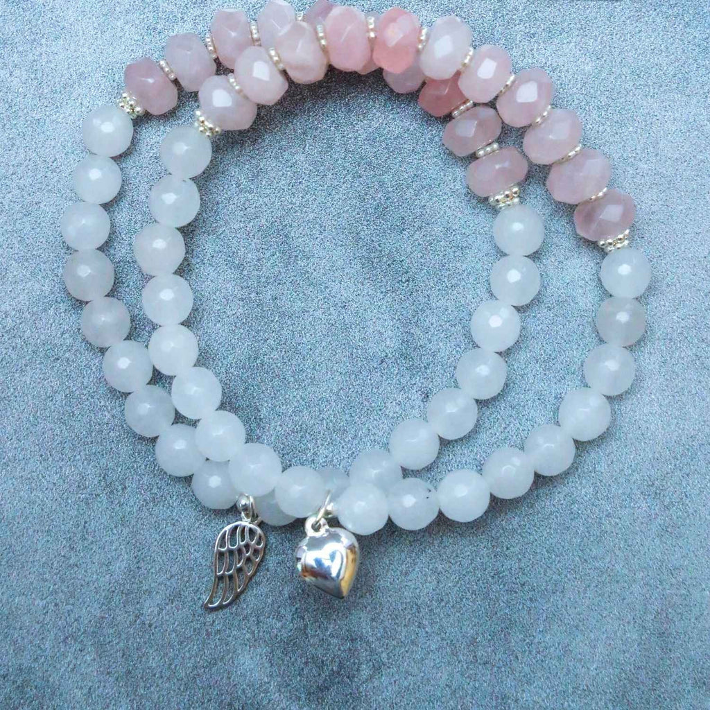 Wing & a Prayer White Jade & Rose Quartz Bracelet - Gemstone Healing Stretch Bracelets. One bracelet contains a silver wing charm and the other bracelet contains a silver heart charm. Each bracelet has silver spacers.