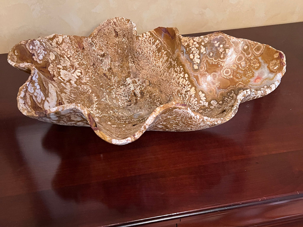 This is a unique polished onyx fossil It is extra large with rough scalloped edges and design. The coloring is honey, cream, brown with a touch of opal. You will also find some fossil-like holes.