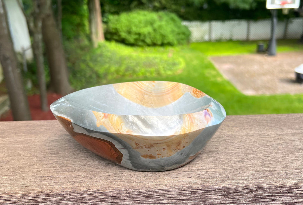 This Medium Polychrome Jasper Stone Bowl is from Madagascar. Hand carved and polished and is a lovely airy and earthy, mysterous, fiery hues, and unique shape. There are very deep burnt orange and burgandy circular spots on the bottom.